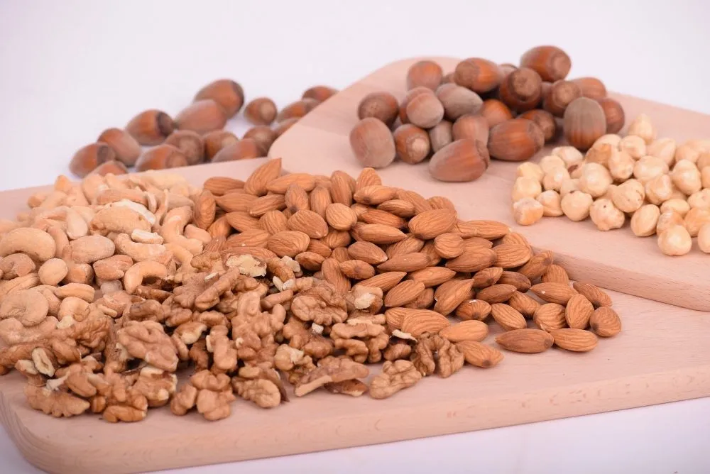 BRCGS Allergen Requirements: BRCGS, SALSA & ISO 22000 Allergen Audit Guide for UK Food Manufacturers 2 Various nuts including walnuts, cashews, almonds, hazelnuts, and chickpeas arranged on wooden boards.
