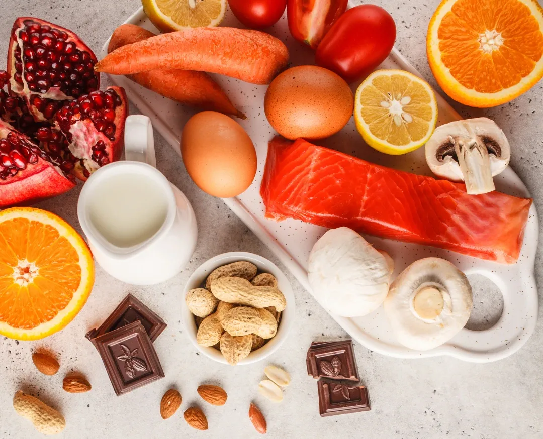 Assortment of common allergenic foods including nuts, eggs, milk, fish, citrus, chocolate, and mushrooms on a table.
