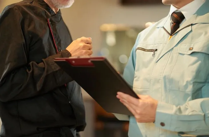 Two professionals discussing food hygiene in care homes, one holding a clipboard and the other in a chef's jacket.